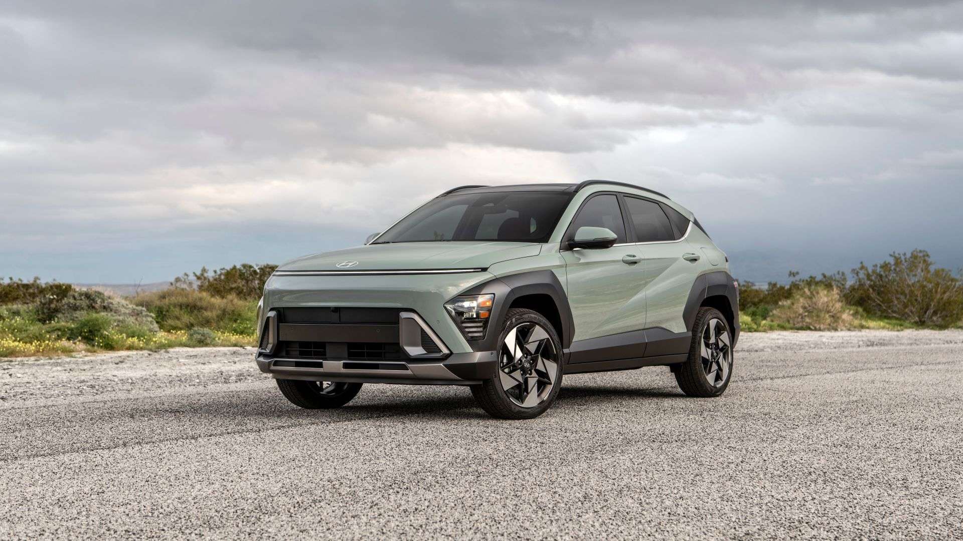 Un petit VUS Hyundai Kona 2024 de couleur Vert Mirage est montré de face sur un ciel orageux.